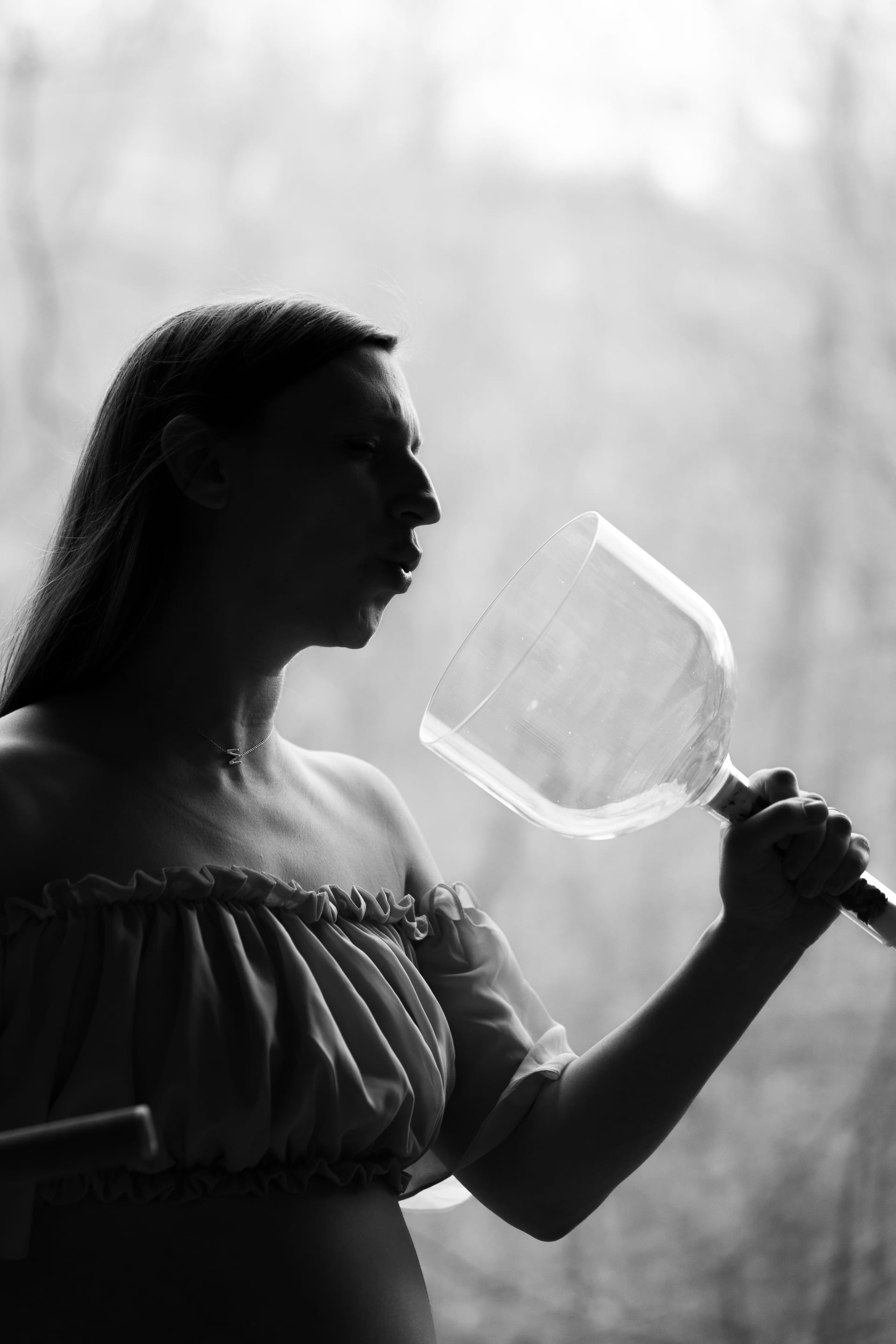 Katie singing into a crystal singing bowl, silhouetted against a bright window